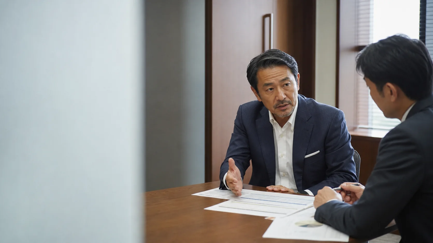 経営者と銀行担当者が長期貸付金の返済条件と回収実績を確認する会議