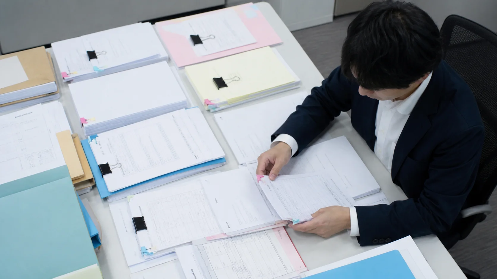 中小企業の財務担当者が未収入金の取引別明細と回収証拠を照合する場面