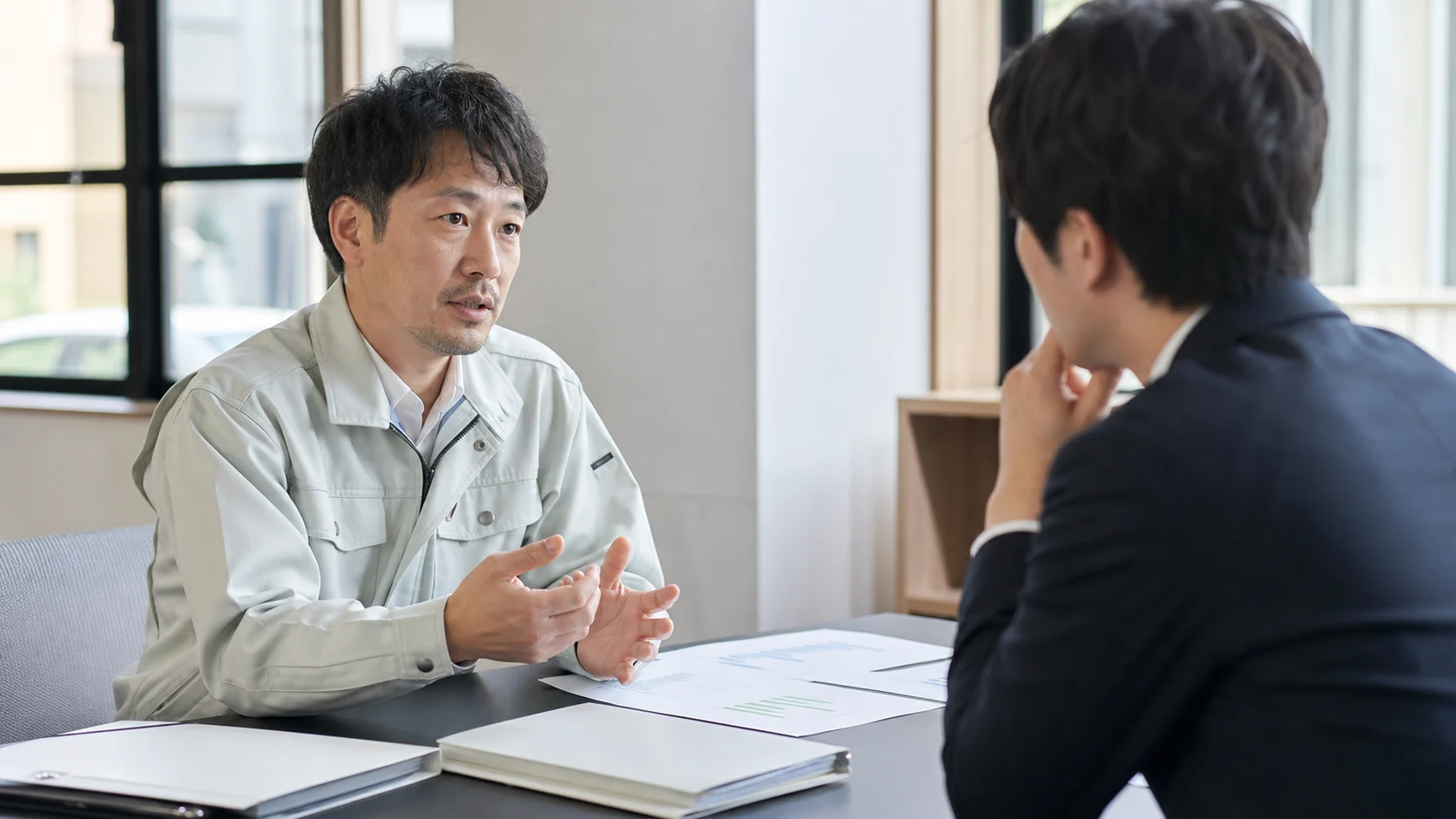 事業者と金融機関担当者が許認可更新の遅延と事業継続資金を協議する場面