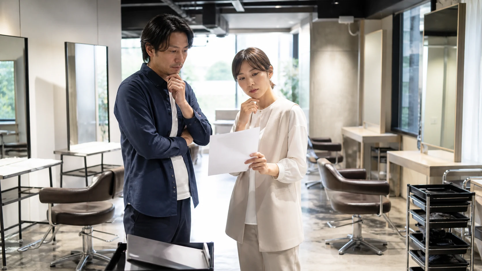 美容サロンの経営者と店長が改装中の店内で席・設備・人員計画を確認する場面